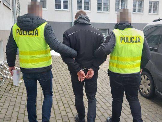 Policjanci prowadzą zatrzymanego mężczyznę.