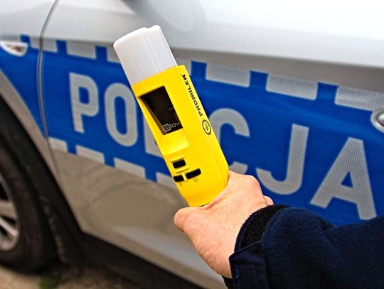Alkomat na tle radiowozu policji.