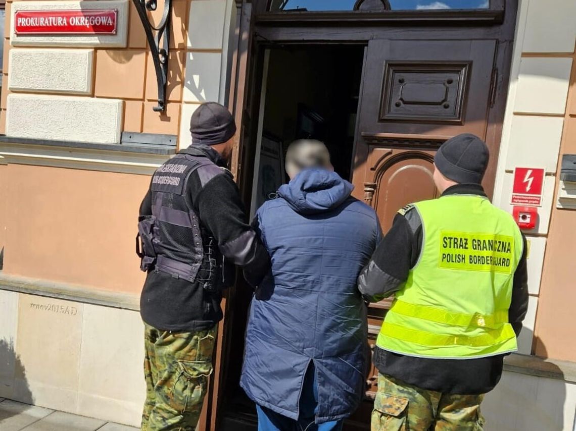 Funkcjonariusze prowadzą poszukiwanego obywatela do zamojskiej prokuratury.